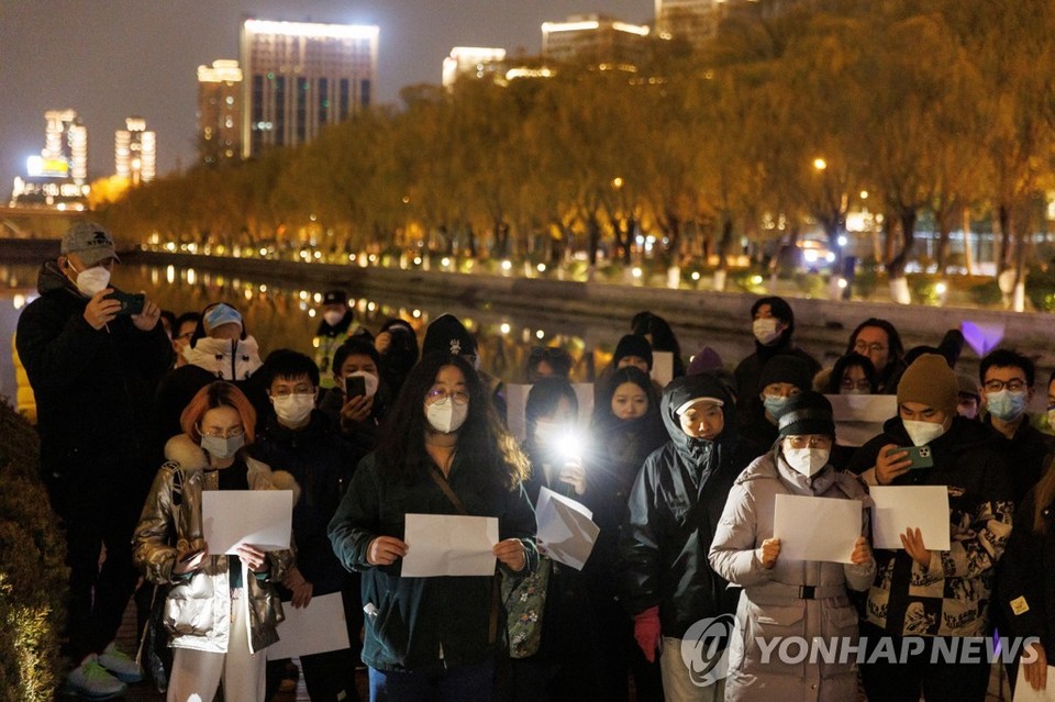 지난 27일 밤 중국 베이징에서 사람들이 백지를 든 채 우루무치 화재 희생자를 추모하고 당국의 제로 코로나 방역에 항의하는 집회를 열었다[로이터=연합뉴스]