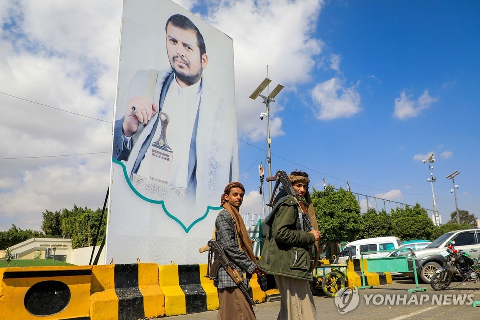 후티 지도자 압둘 말리크 알후티의 대형사진 옆을 지나는 후티 병사들[AFP=연합뉴스]