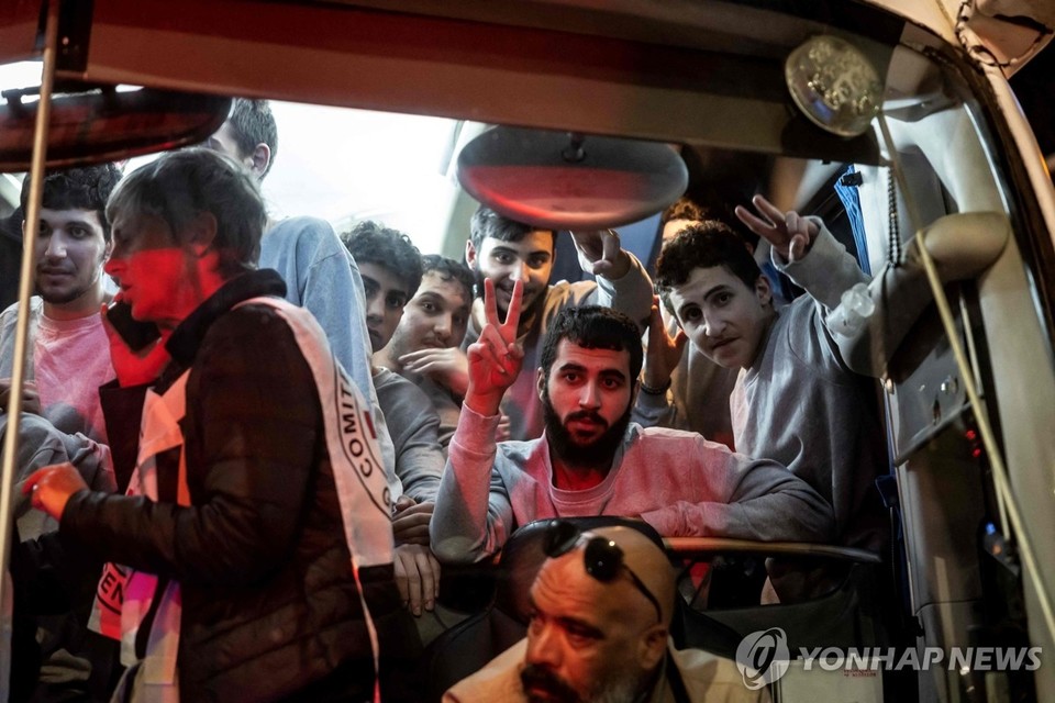 26일(현지시간) 이스라엘에서 풀려난 팔레스타인 수감자들을 태우고 온 적십자사 버스가 요르단강 서안지구 라말라에 도착하고, 버스 안에 타고 있는 사람들이 환영나온 인파를 향해 손으로 승리의 'V' 자를 표시하고 있다. 이스라엘은 이날 39명의 팔레스타인 수감자를 석방했다고 밝혔다[AFP=연합뉴스]